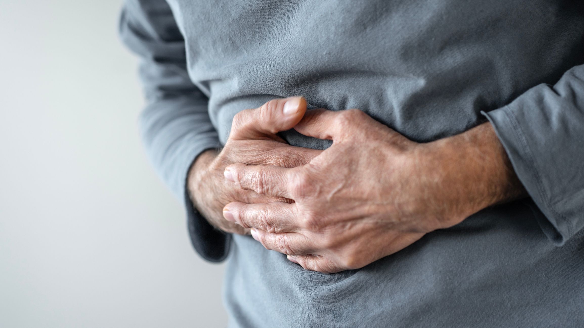 Eldre mann holder seg på magen