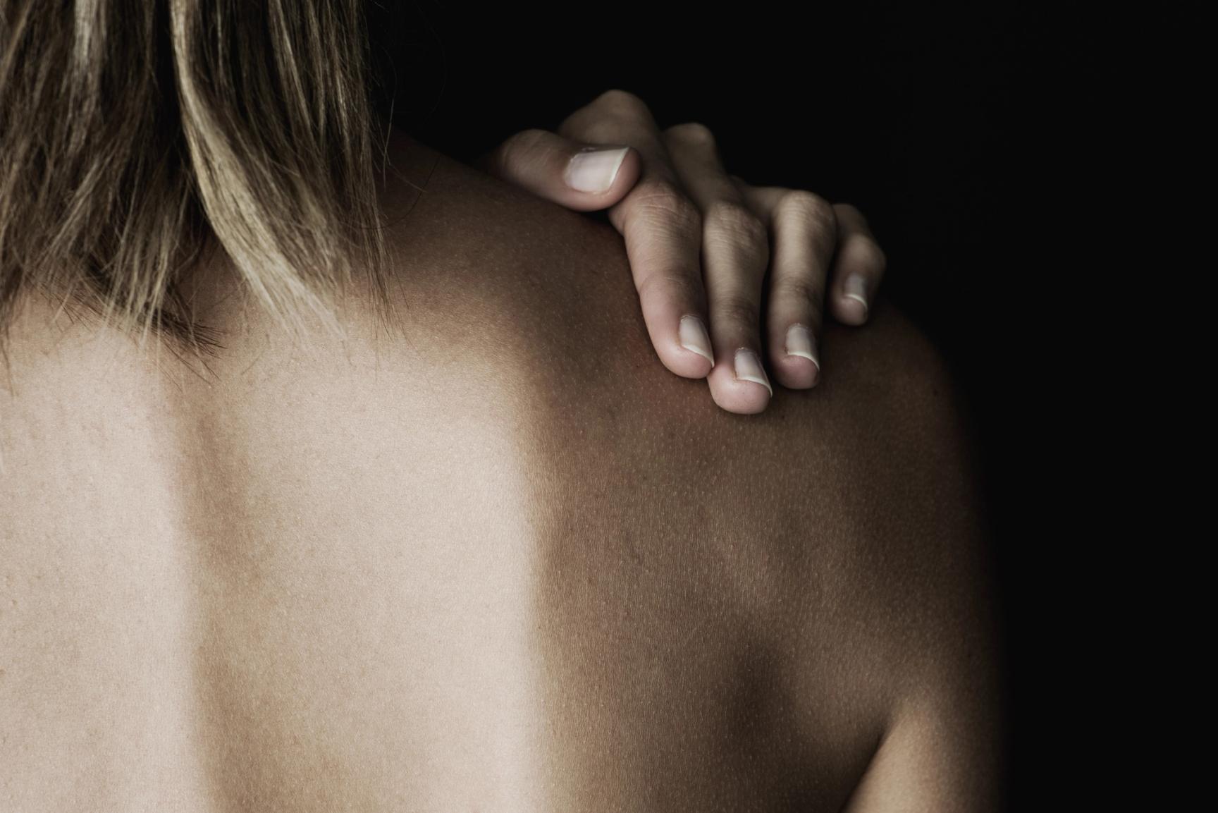 Kvinne holder en hånd på bar skulder