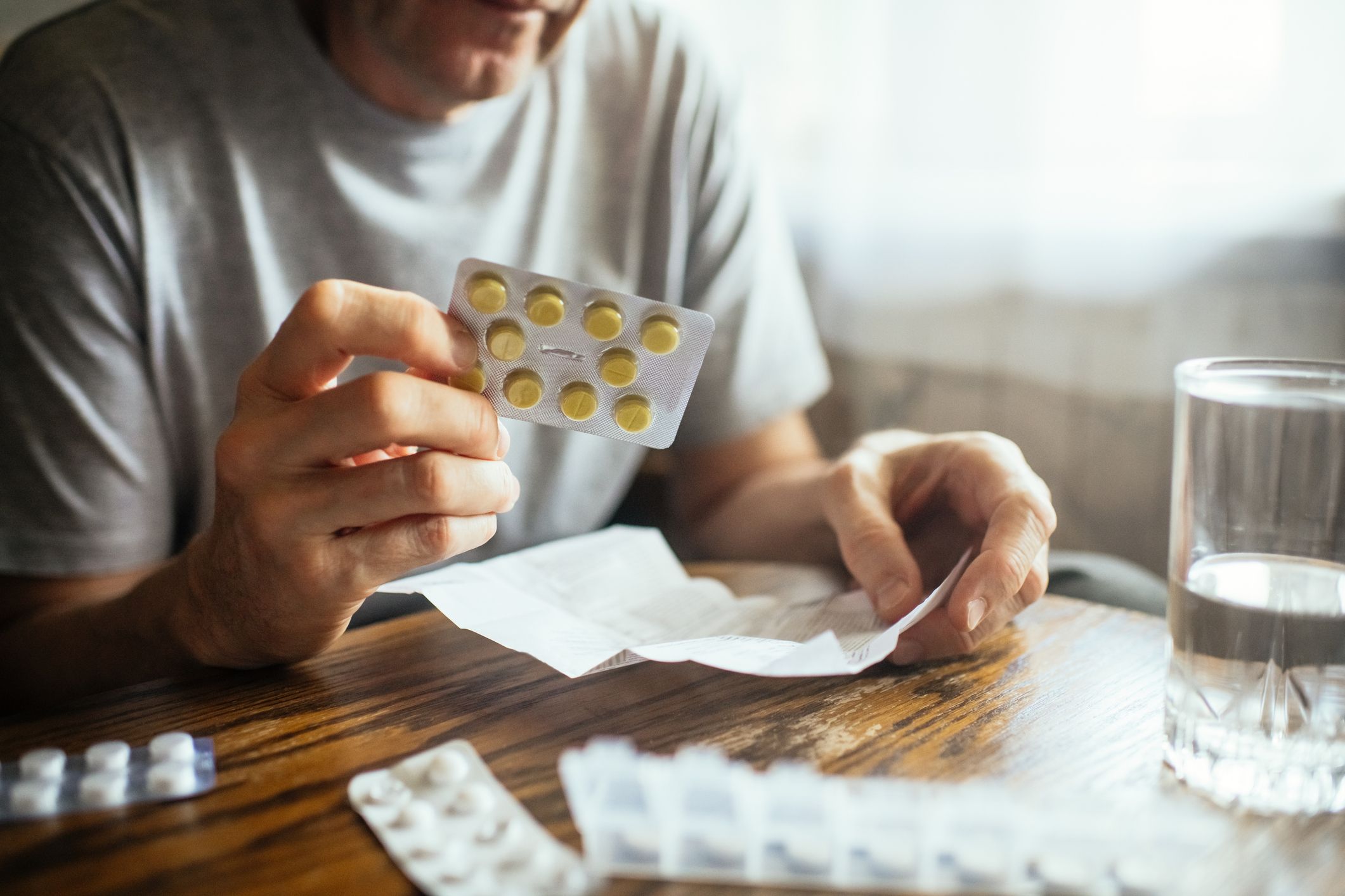 Mann som holder blister med tabletter og leser bruksanvisning