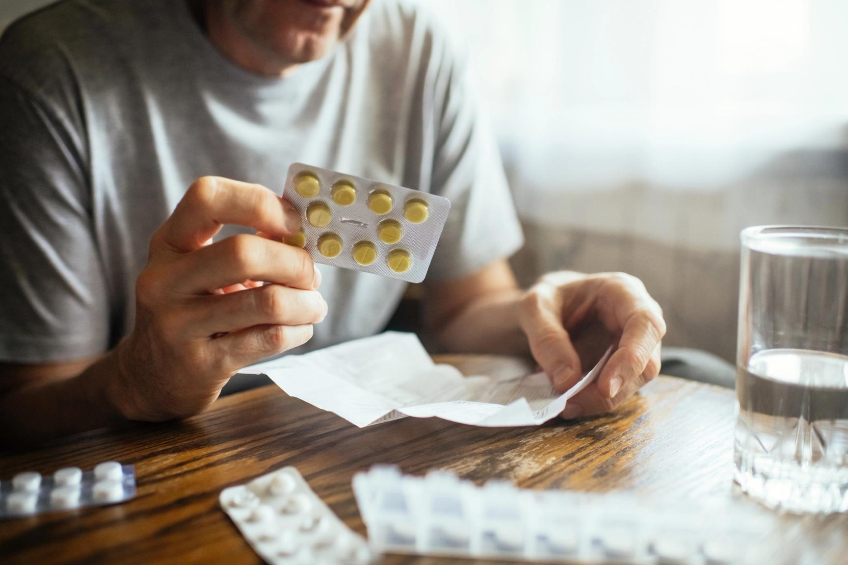 Mann som holder blister med tabletter og leser bruksanvisning