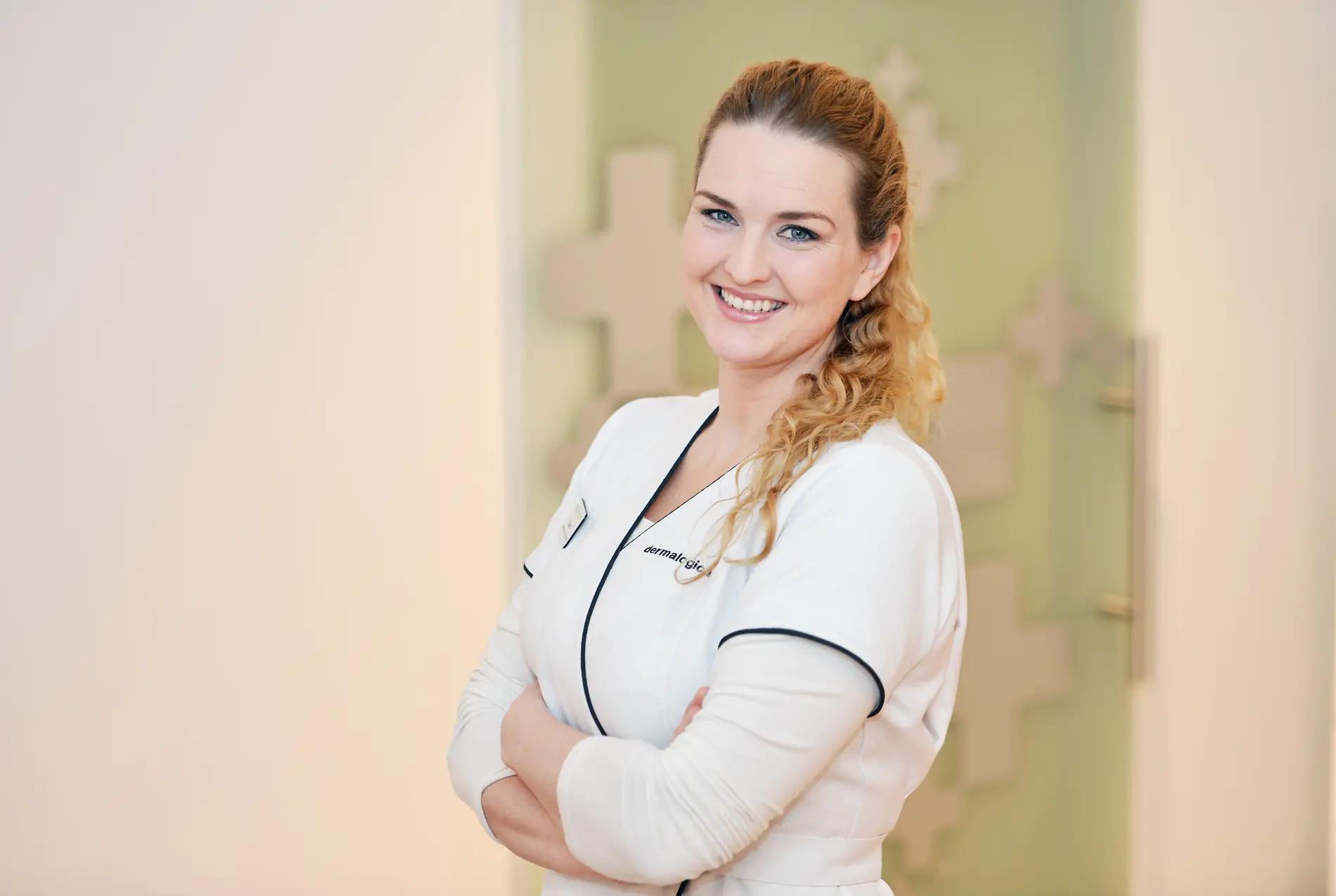 Farmasøyt i uniform smiler og ser i kamera med armene i kors