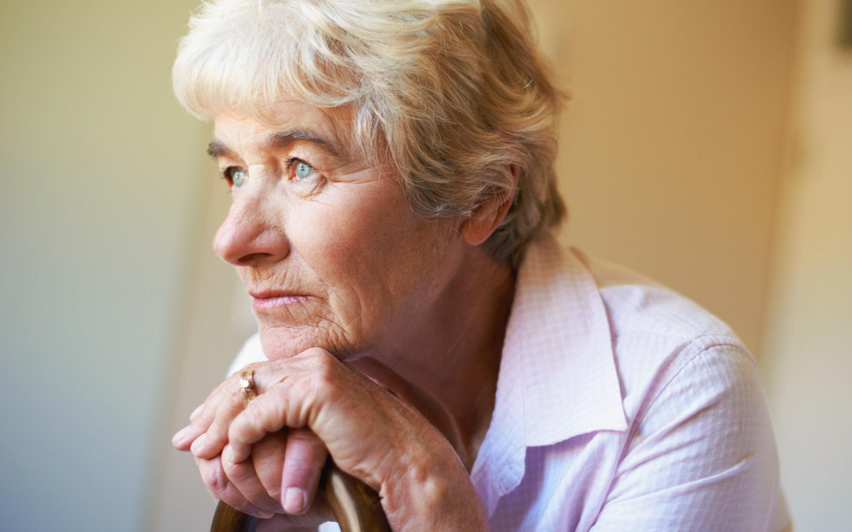 Eldre kvinne som hviler haka på hendene