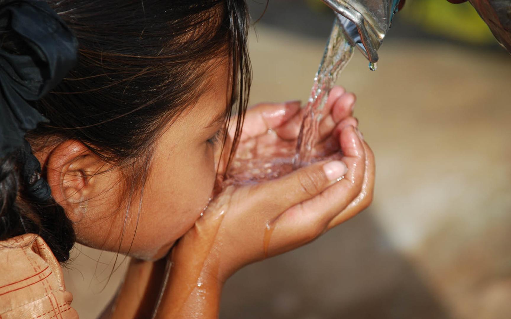 Jente drikker vann fra utekran