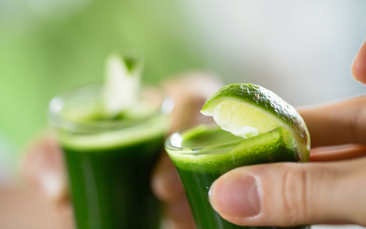 Bilde av to shotglass med grønn drikke og lime. 