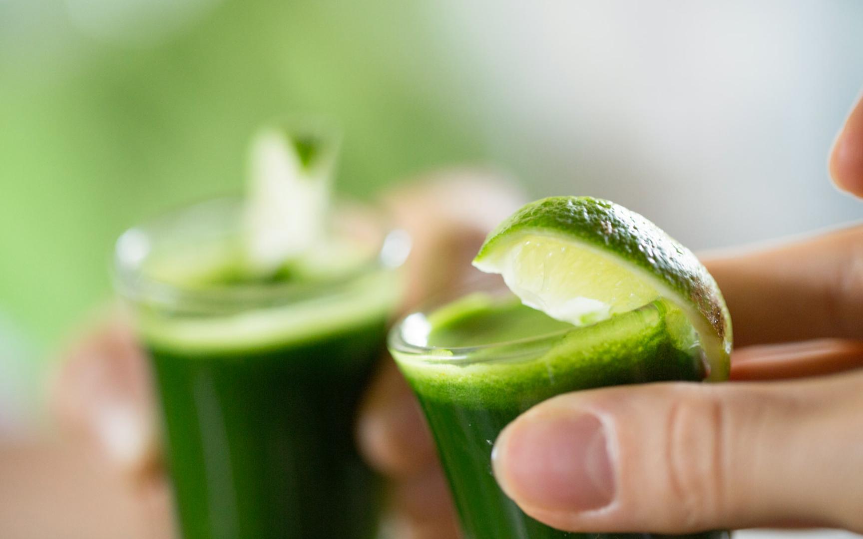 Bilde av to shotglass med grønn drikke og lime.