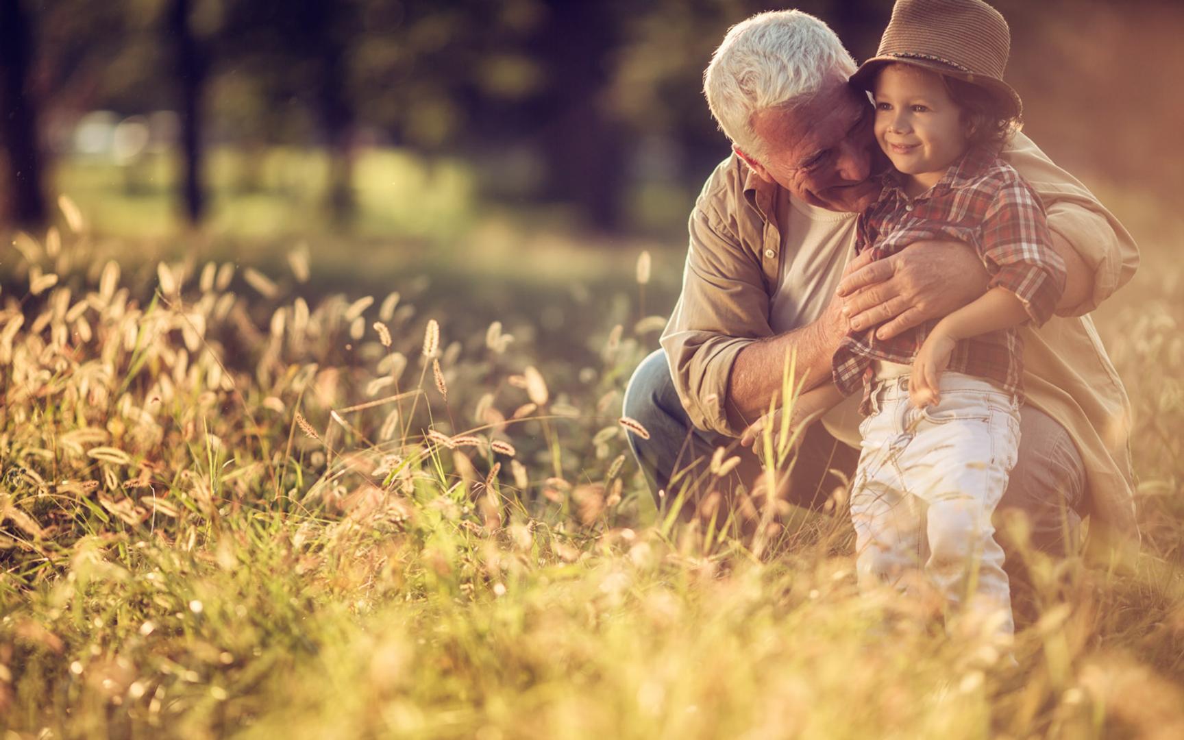 Bilde av en eldre mann holder rundt et barn i korneng.