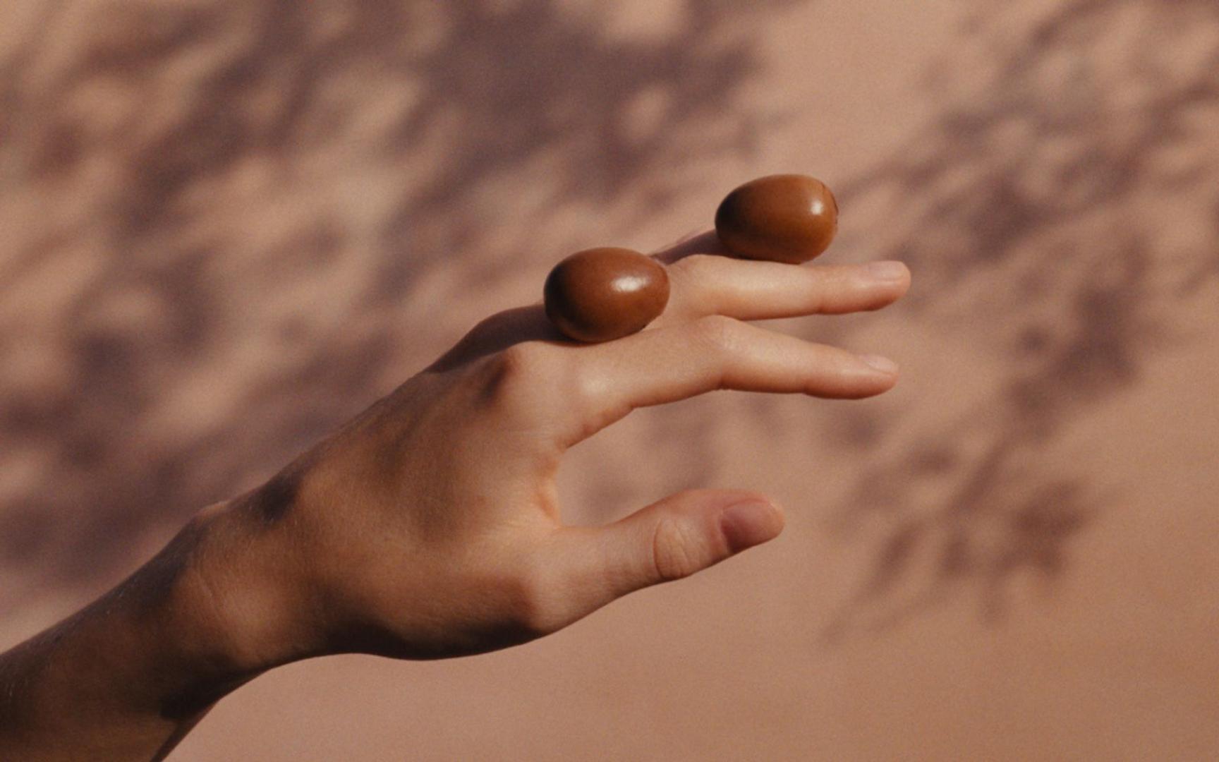 Kvinne med 2 sheanøtter på hånden