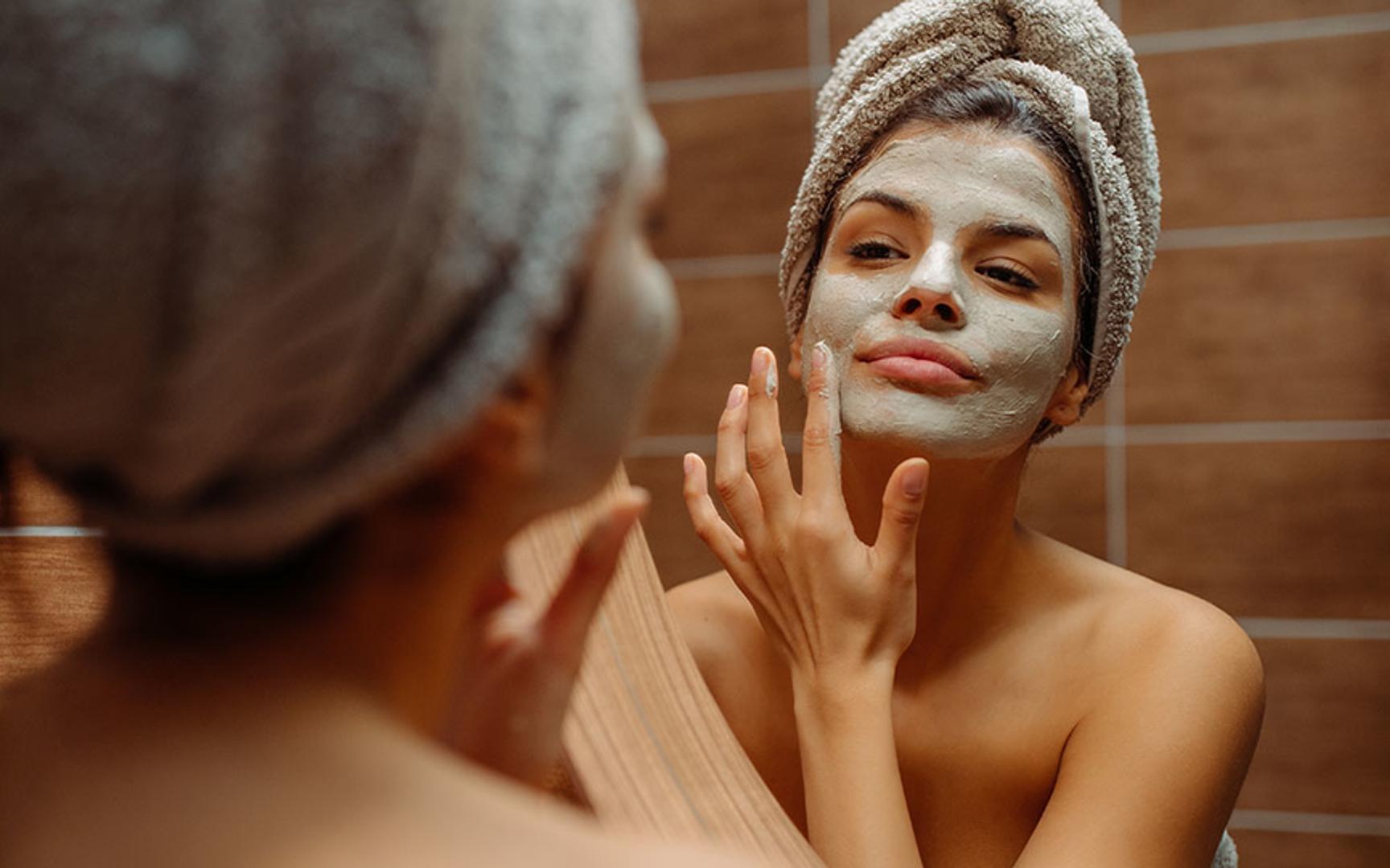 Kvinne som står i speilet og har på ansiktsmaske