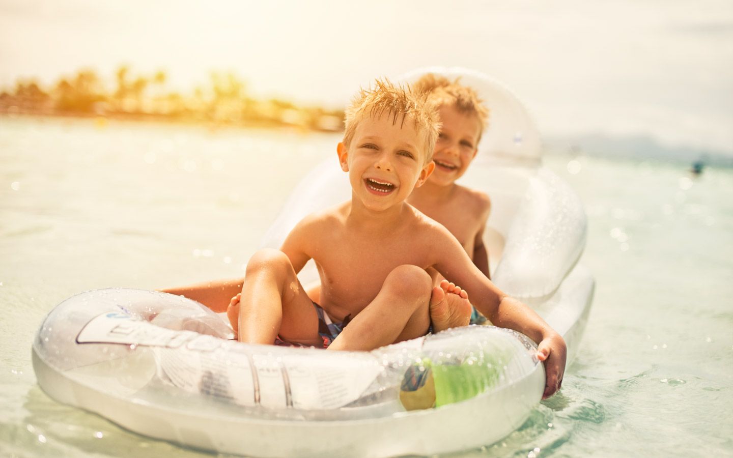 Bilde av to barn sittende i en oppblåsbar stol ute på vannet. 