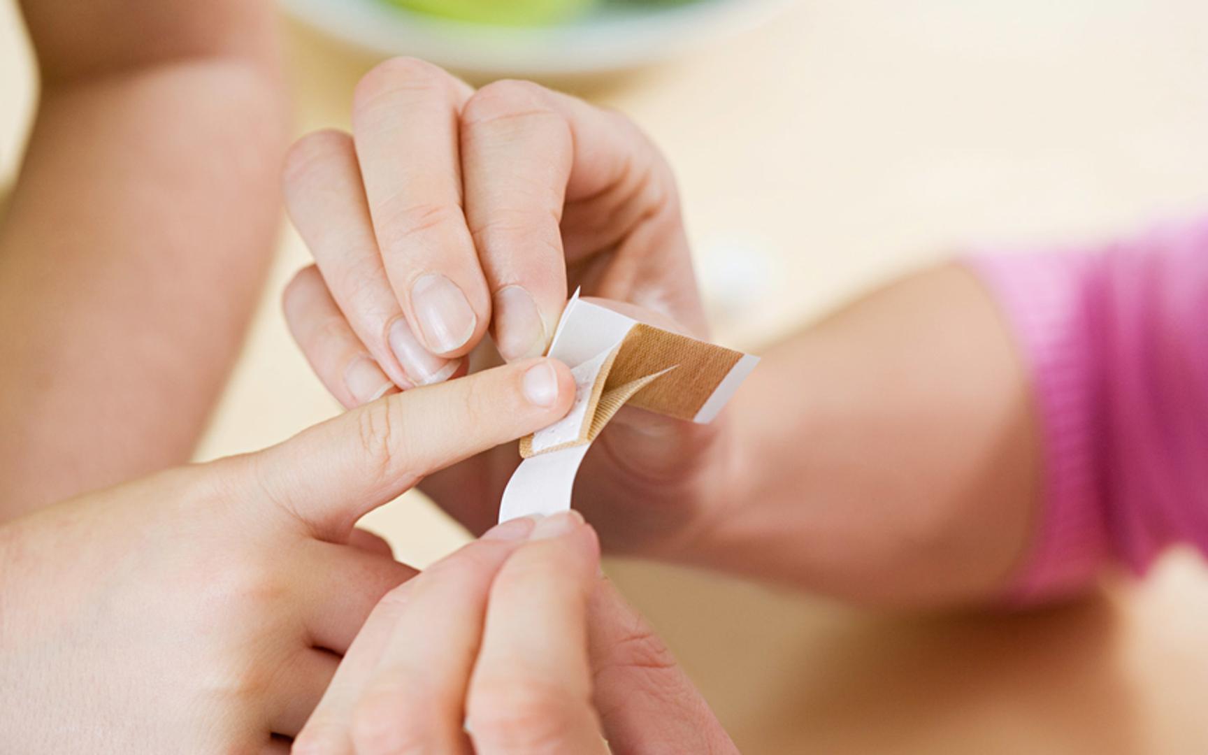 Barn som får plaster på finger av en voksen
