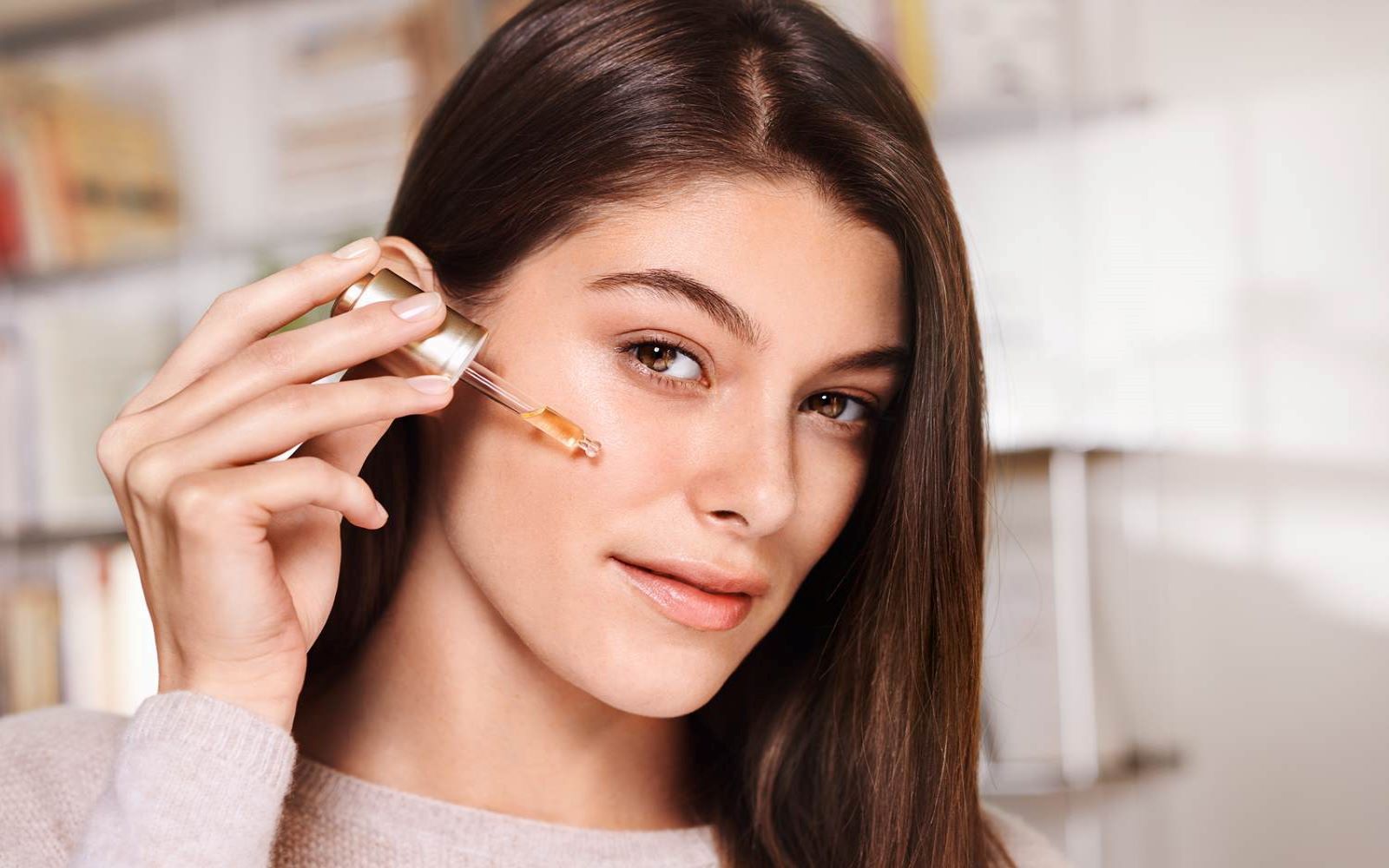 Kvinne som påfører hudpleieprodukt i ansiktet med pipette