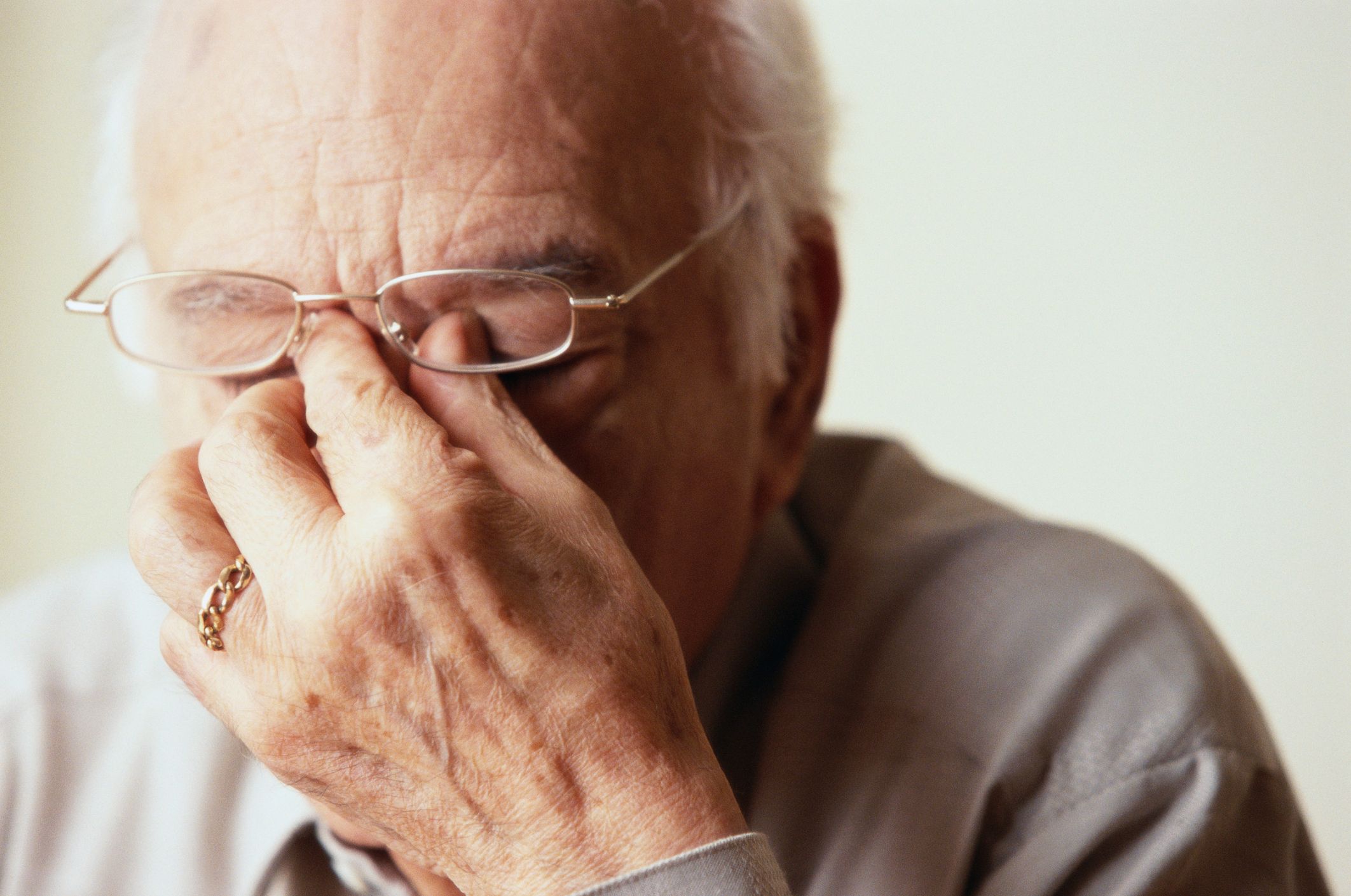 Eldre mann lukker øynene og niper seg ved neseroten