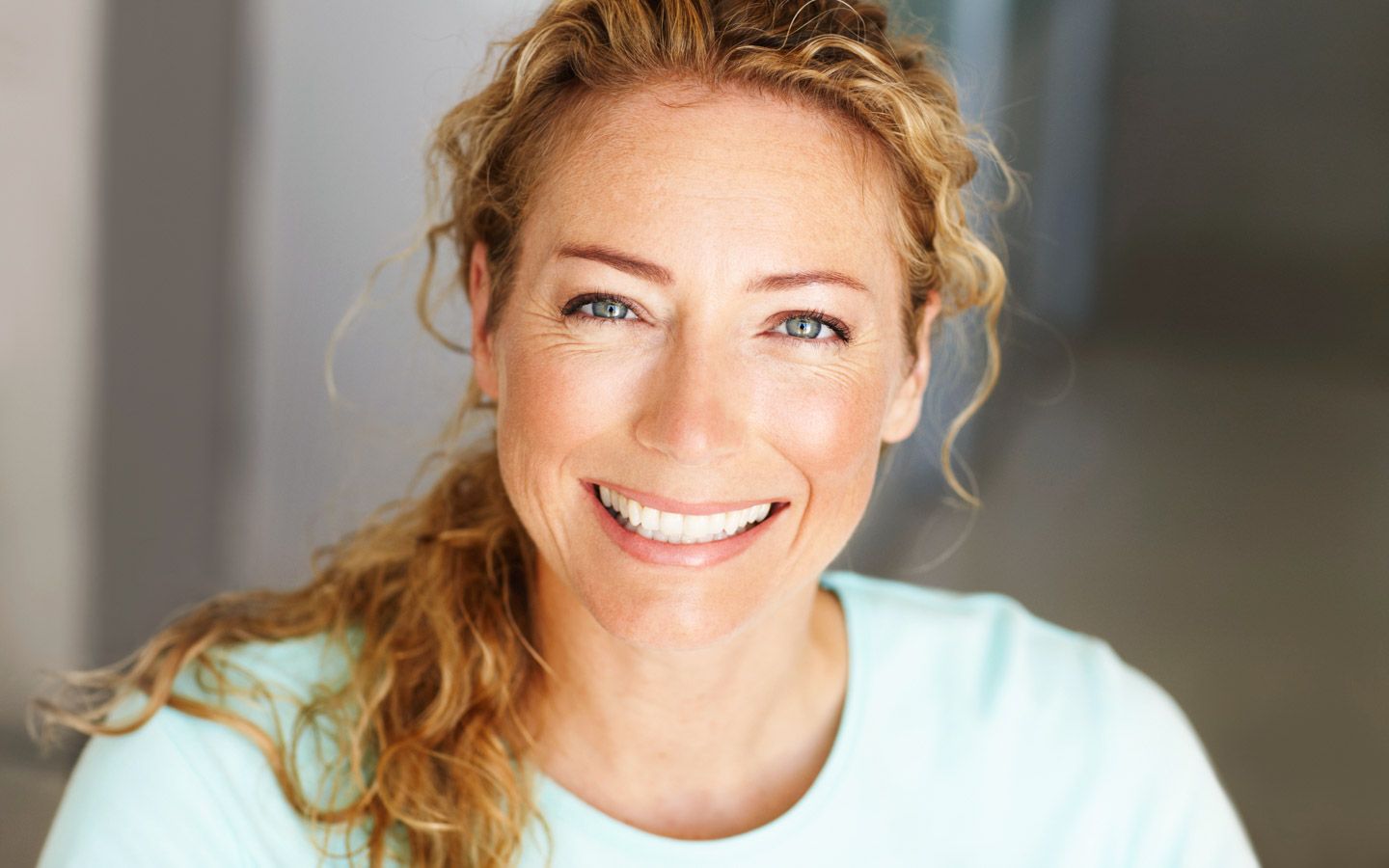 Bilde av ansikt til en dame som smiler og har lyse krøller. 