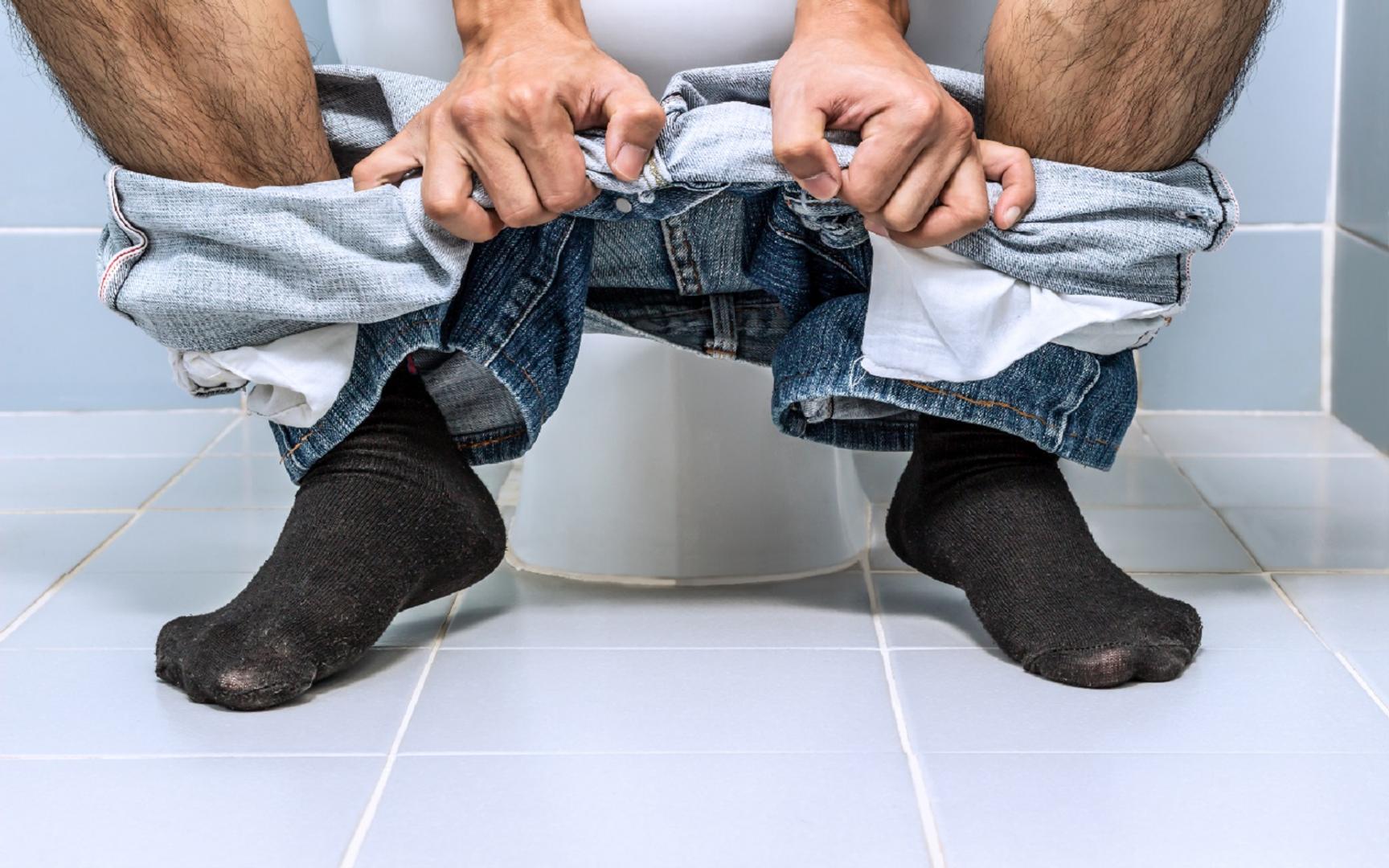 Benene til en person som sitter på toalettet