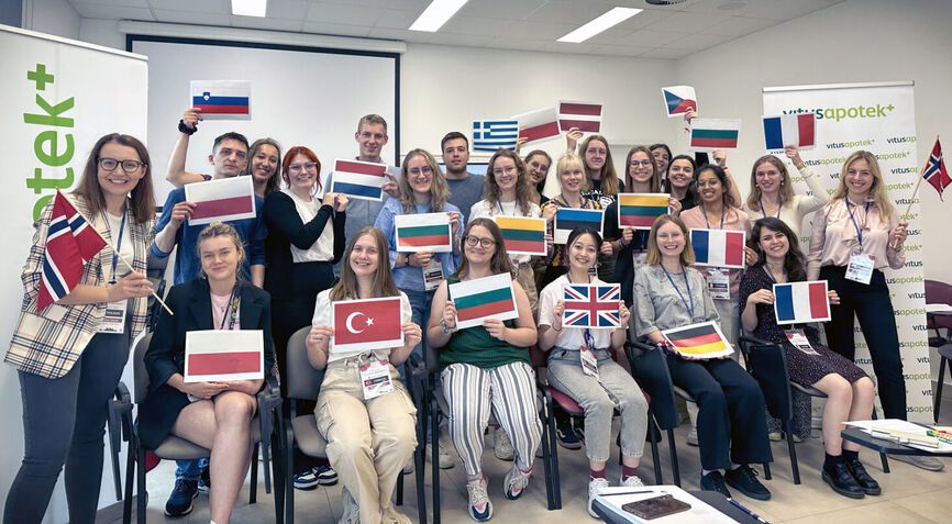 A group of international students smiling, each holding their home country’s flag.