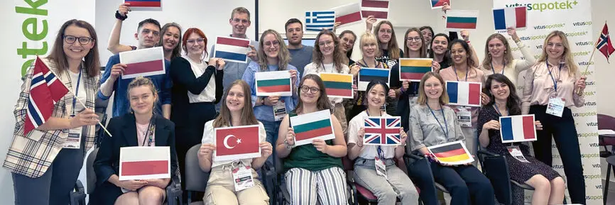 A group of international students smiling, each holding their home country’s flag.