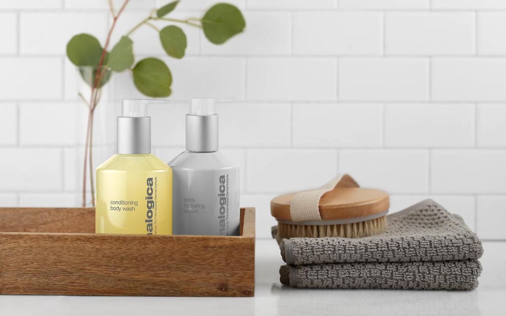 Et brunt brett med to dermalogica produkter. To grå klut ved siden av med kroppskrubb