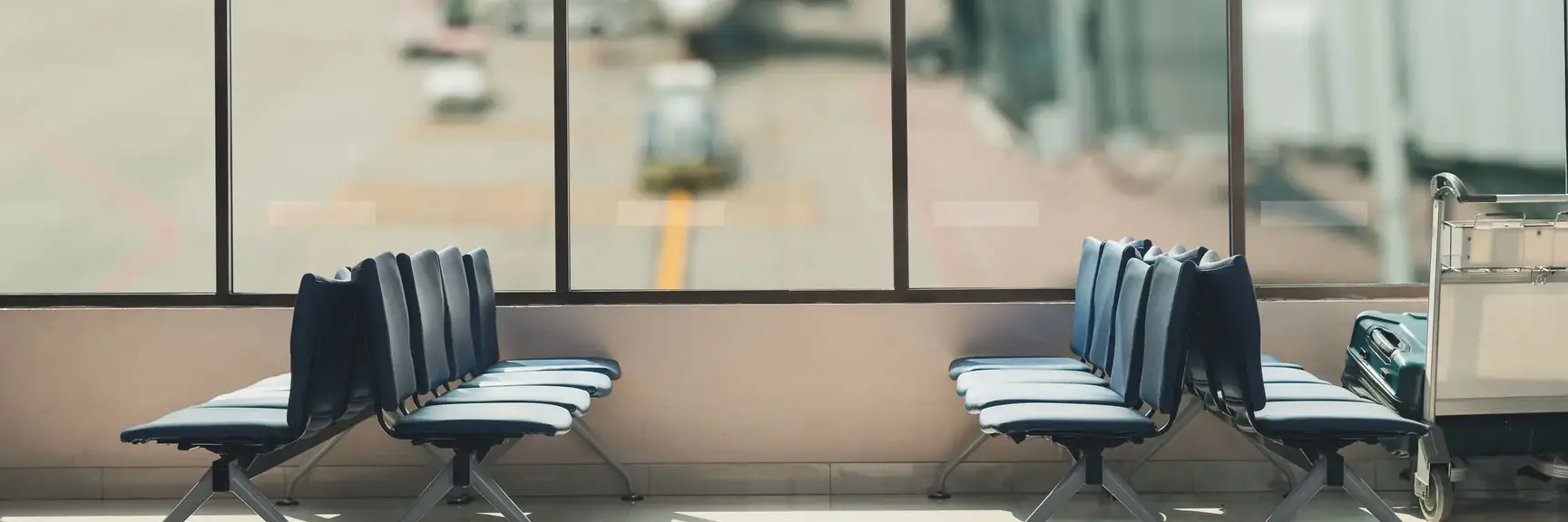 Ventesone på en flyplass, med tomme seter og et fly som lastes i bakgrunnen