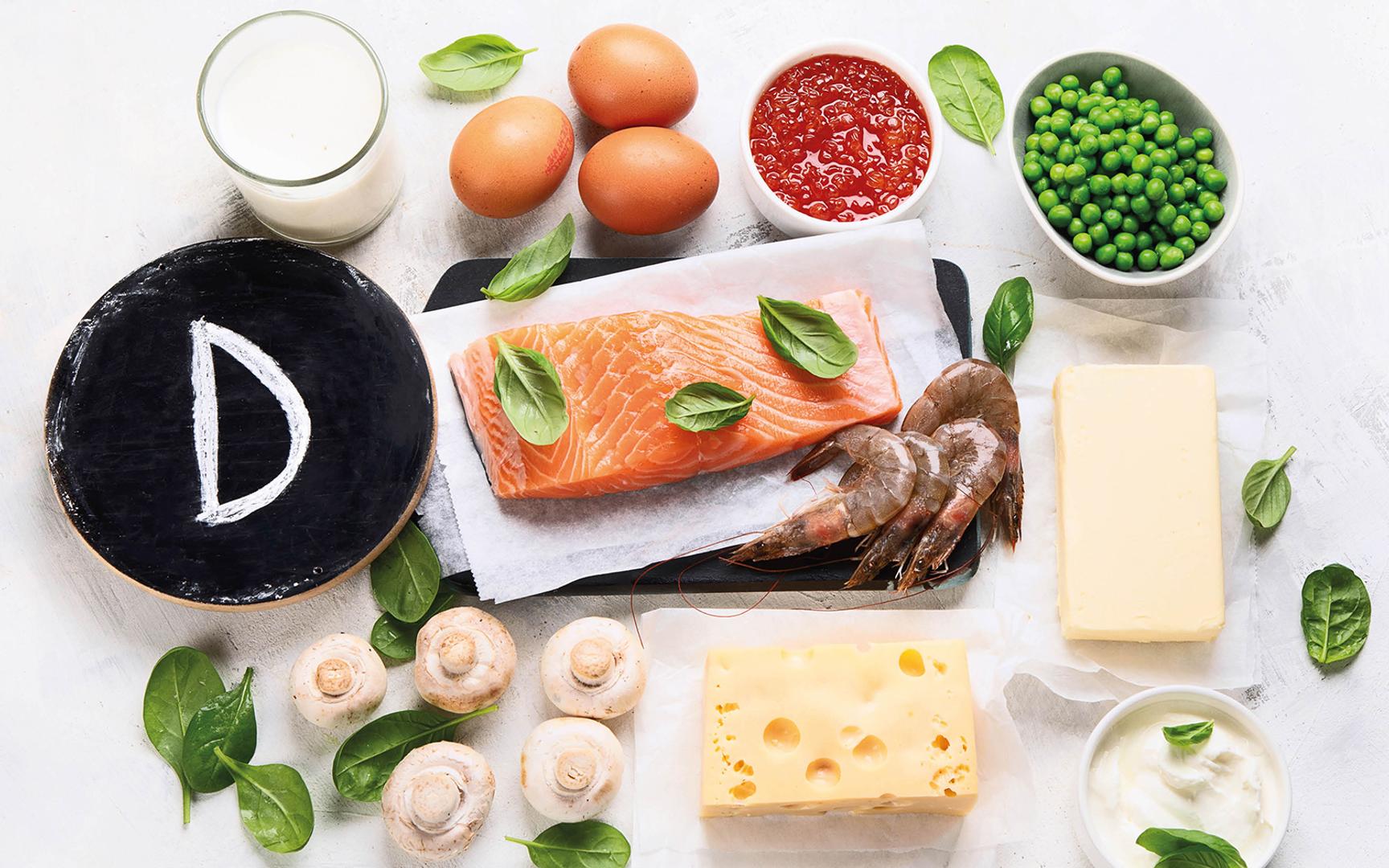 Illustrasjon av matvarer rike på vitamin D, som laks, egg, ost, melk, reker, sopp og erter.
