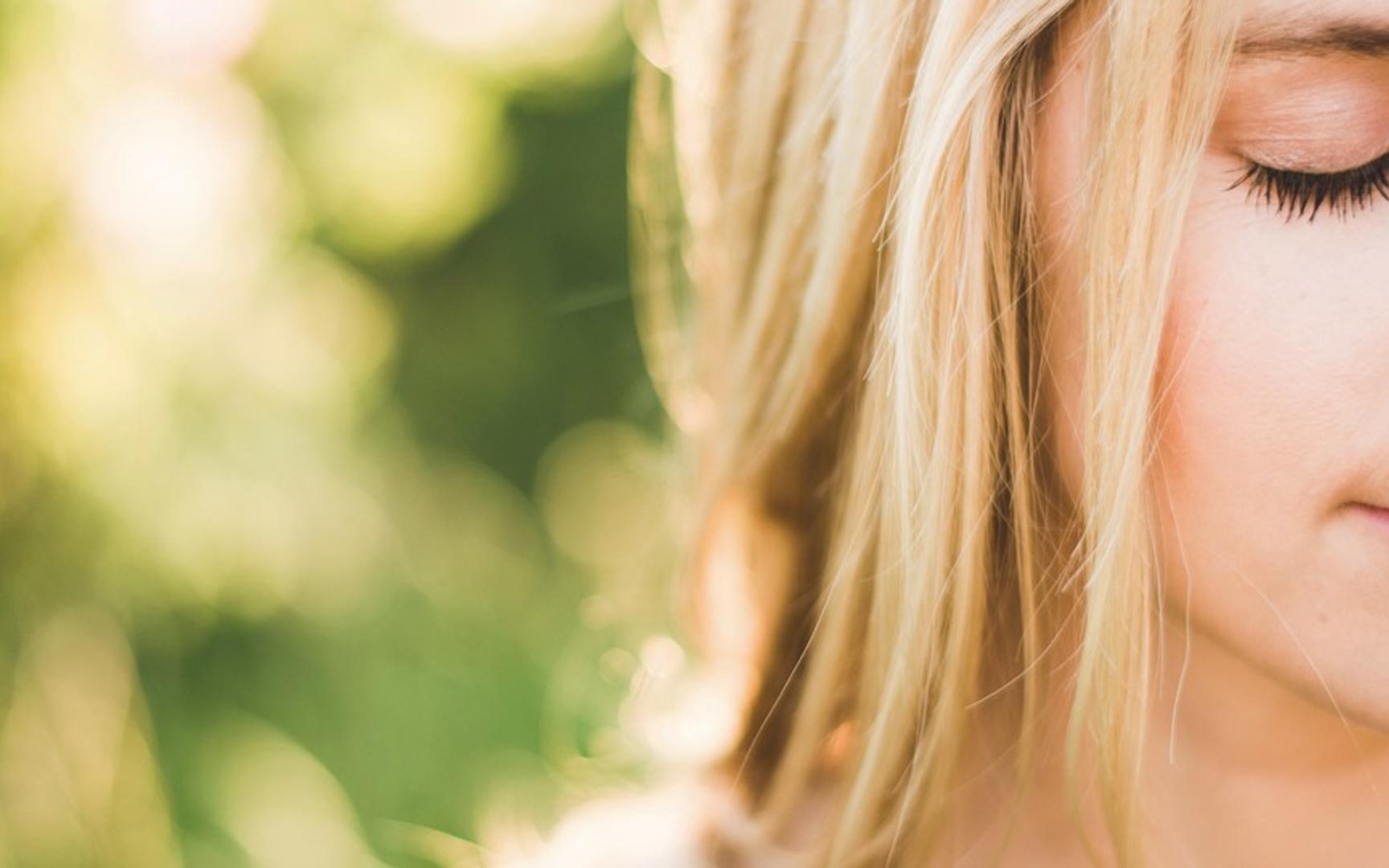 Halve ansiktet til en blond kvinne med gyllen grønn og gul bakgrunn