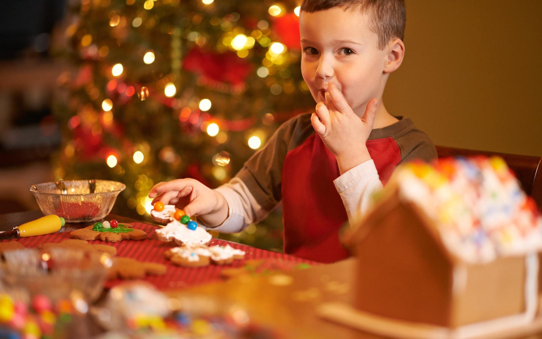 En liten gutt som sitter ved bordet og pynter pepperkaker