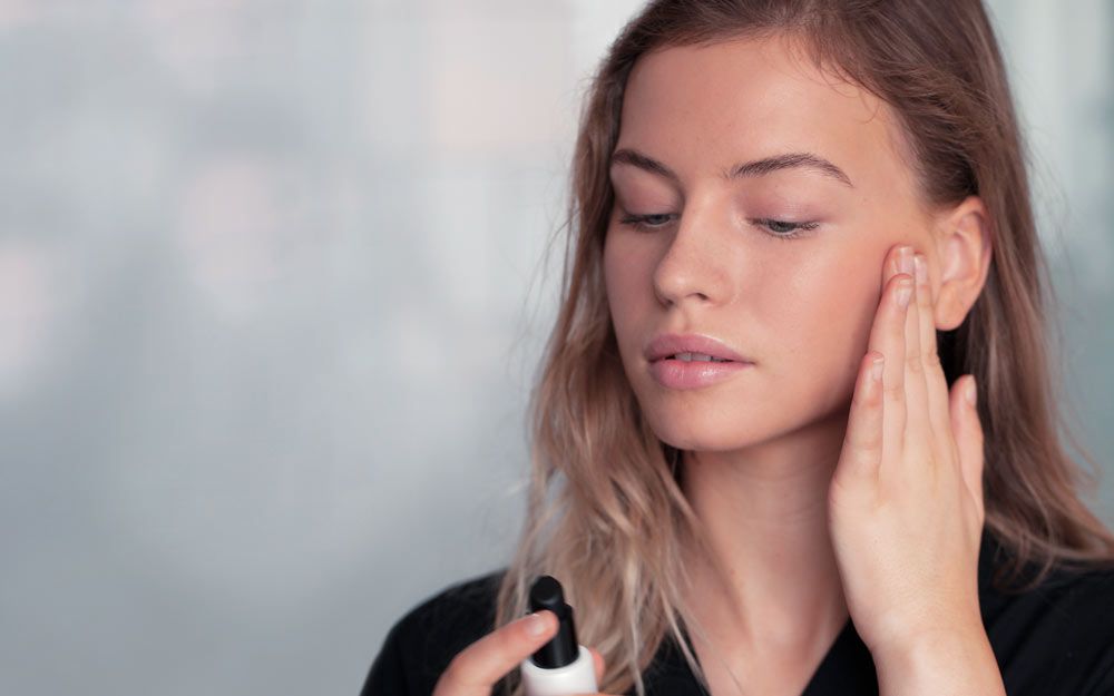 En jente som ser ned på et produkt hun holder i den ene hånden, mens hun tar den andre hånden på kinnet.