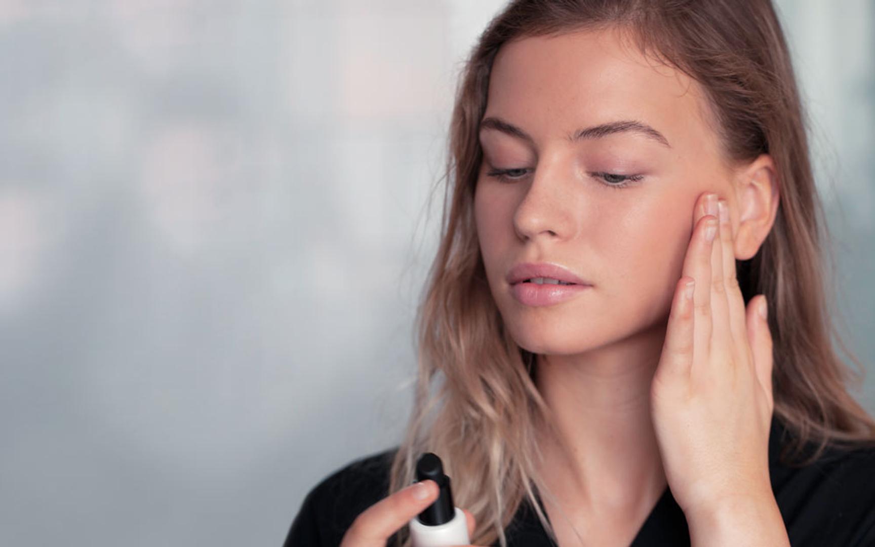 En jente som ser ned på et produkt hun holder i den ene hånden, mens hun tar den andre hånden på kinnet.