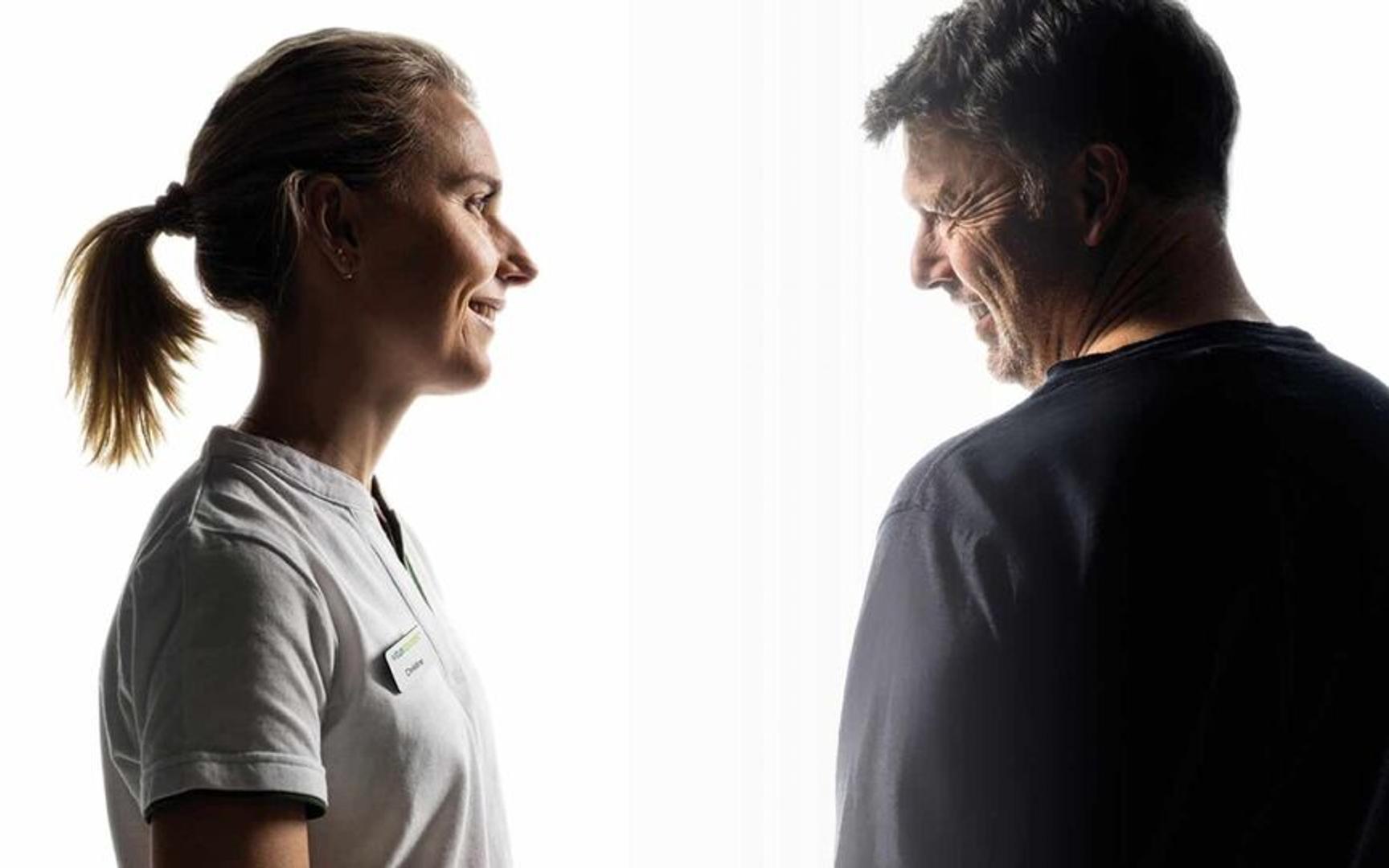 En farmasøyt som ser på og smiler til en mann.