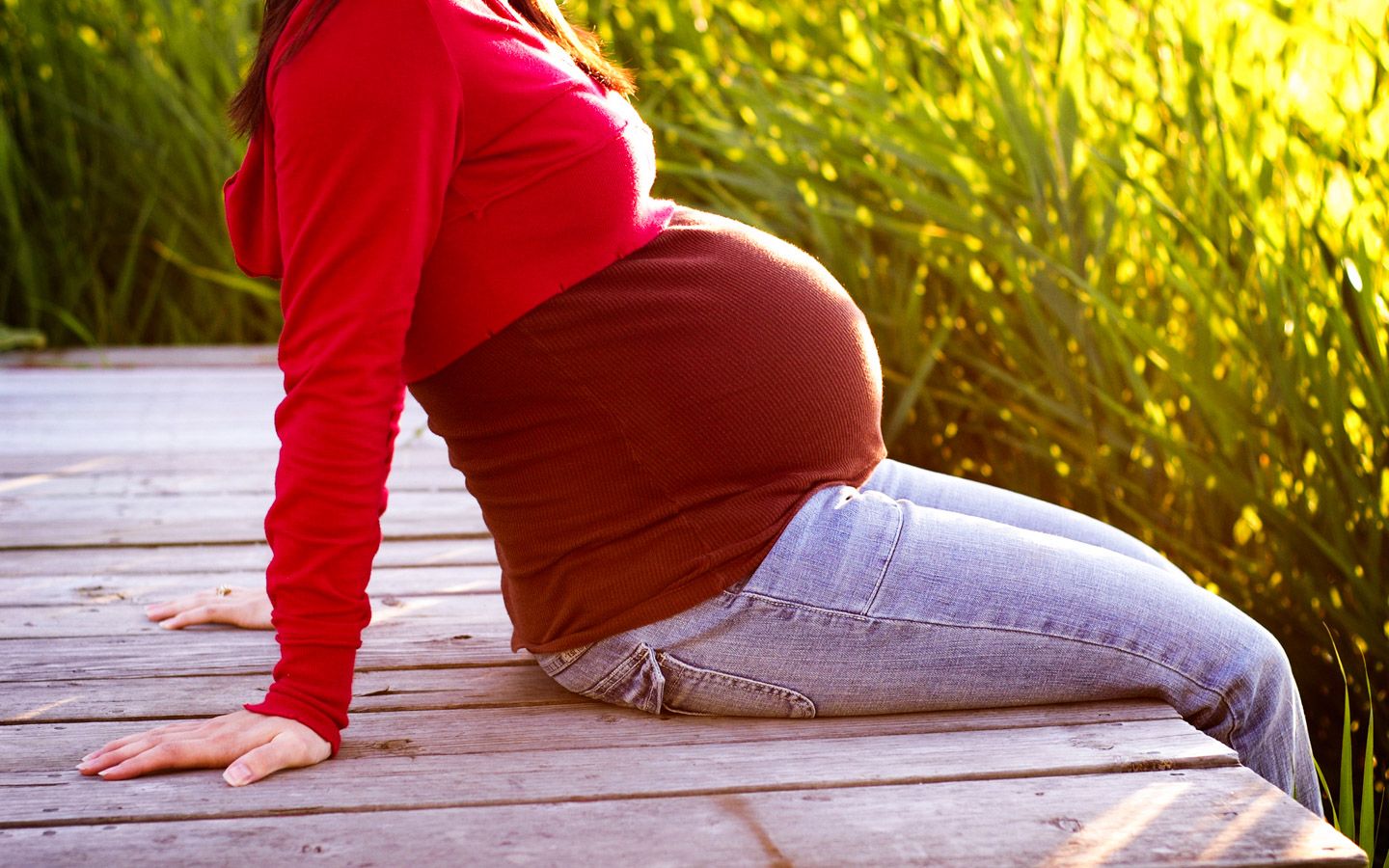 Gravid kvinne som sitter på brygge