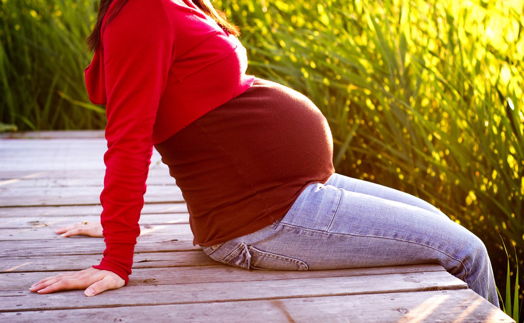 Gravid kvinne som sitter på brygge