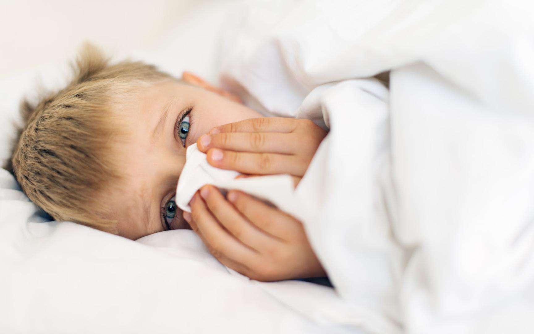 Bilde av et barn som ligger i sengen og holder dynen rundt nesen.