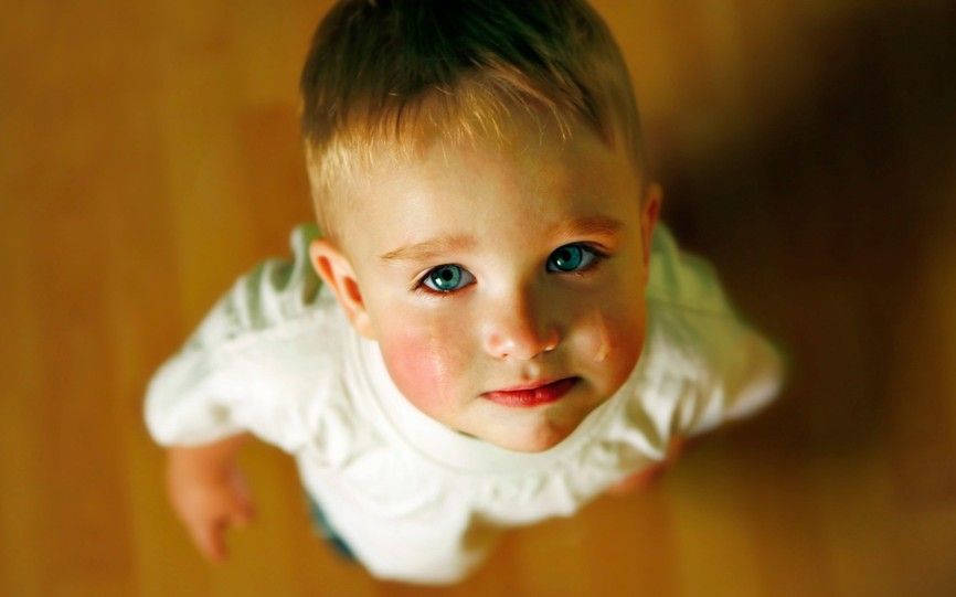 En liten gutt står med tårer å øynene og ser opp mot kameraet