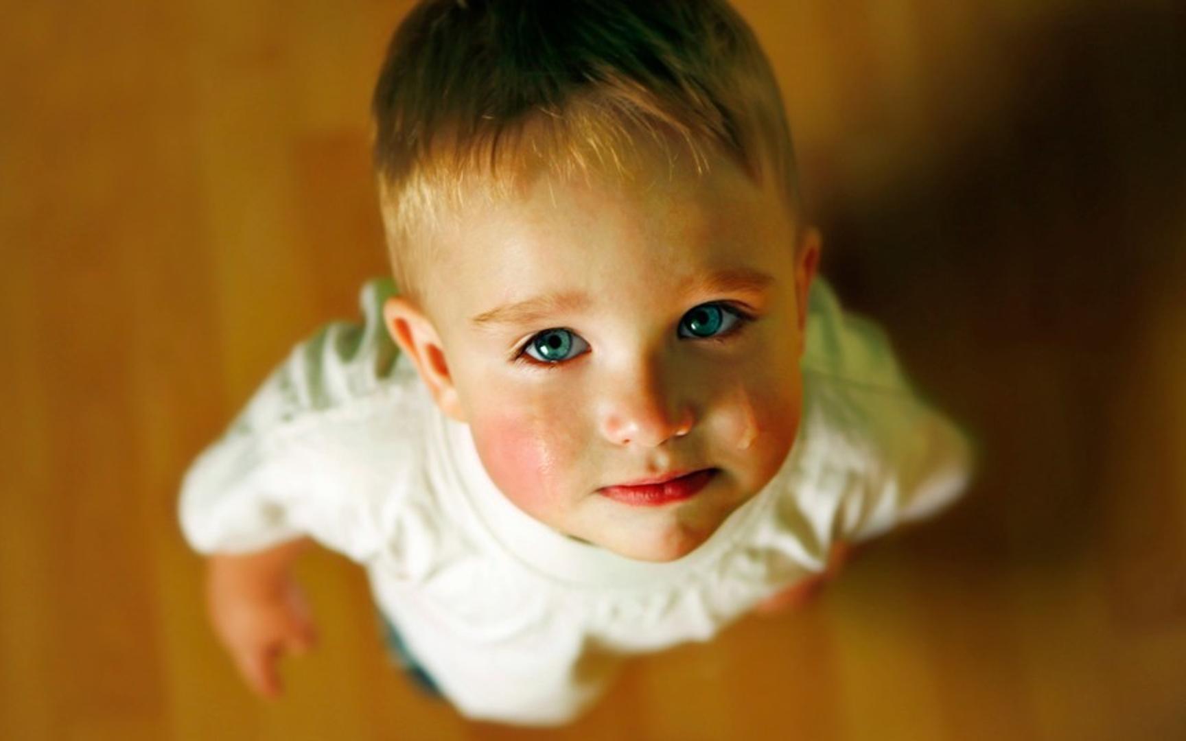 En liten gutt står med tårer å øynene og ser opp mot kameraet