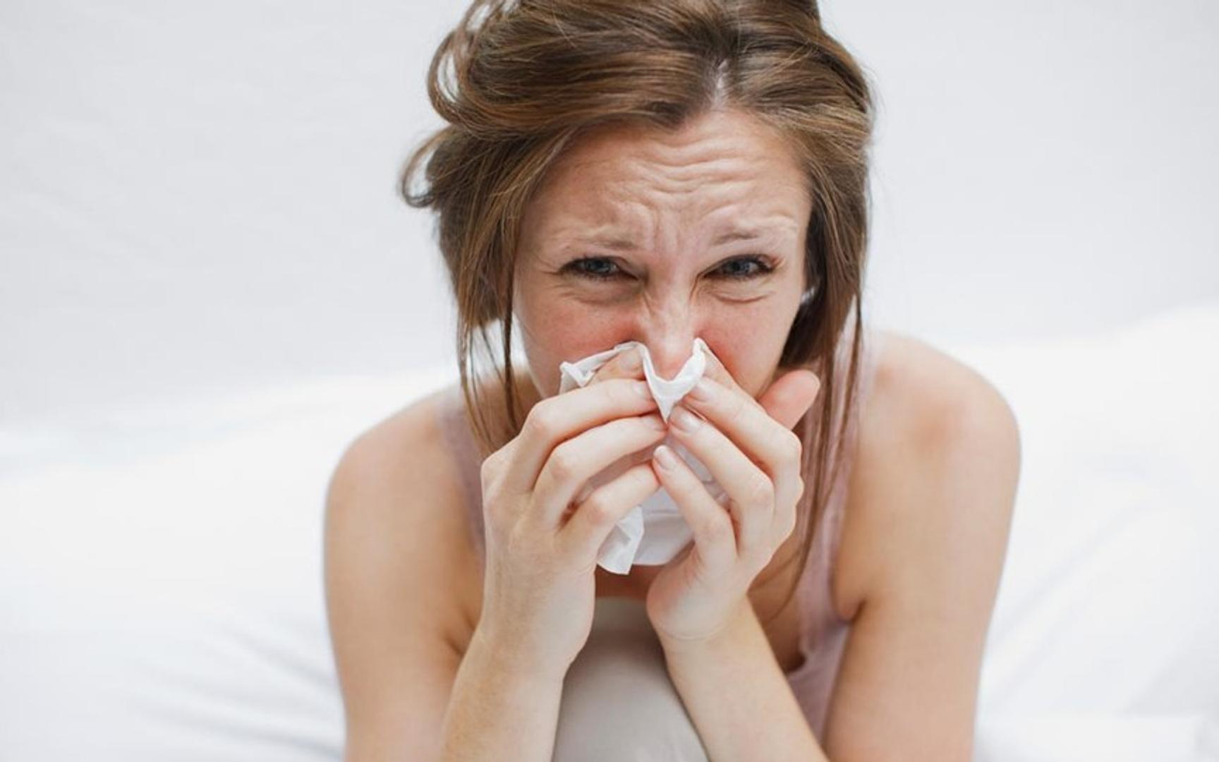 En kvinne pusser nesen med et papir lommetørkle