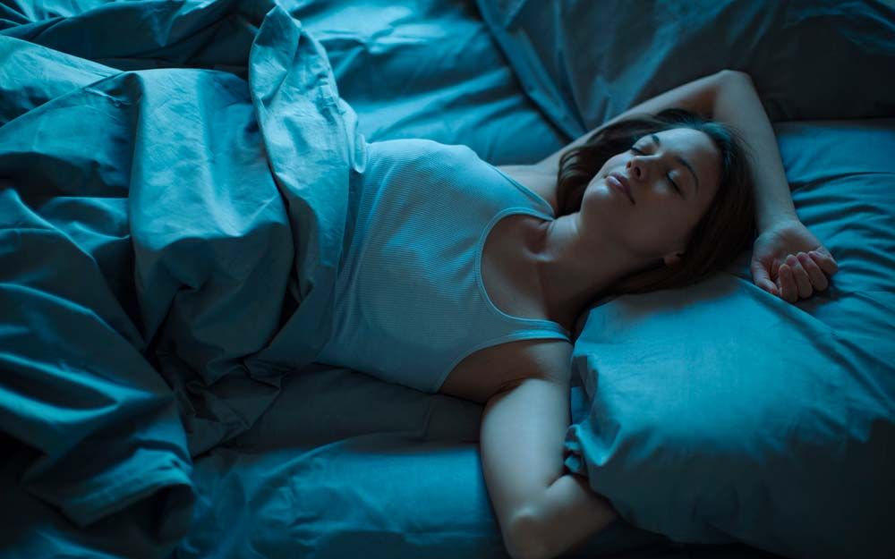 En dame ligger i en seng og sover
