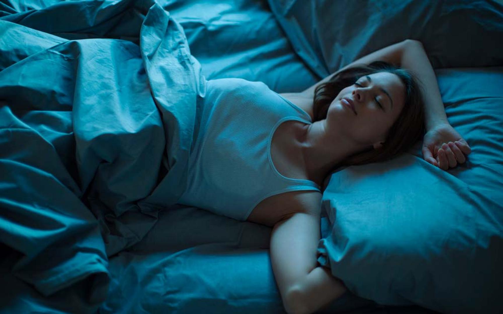 En dame ligger i en seng og sover