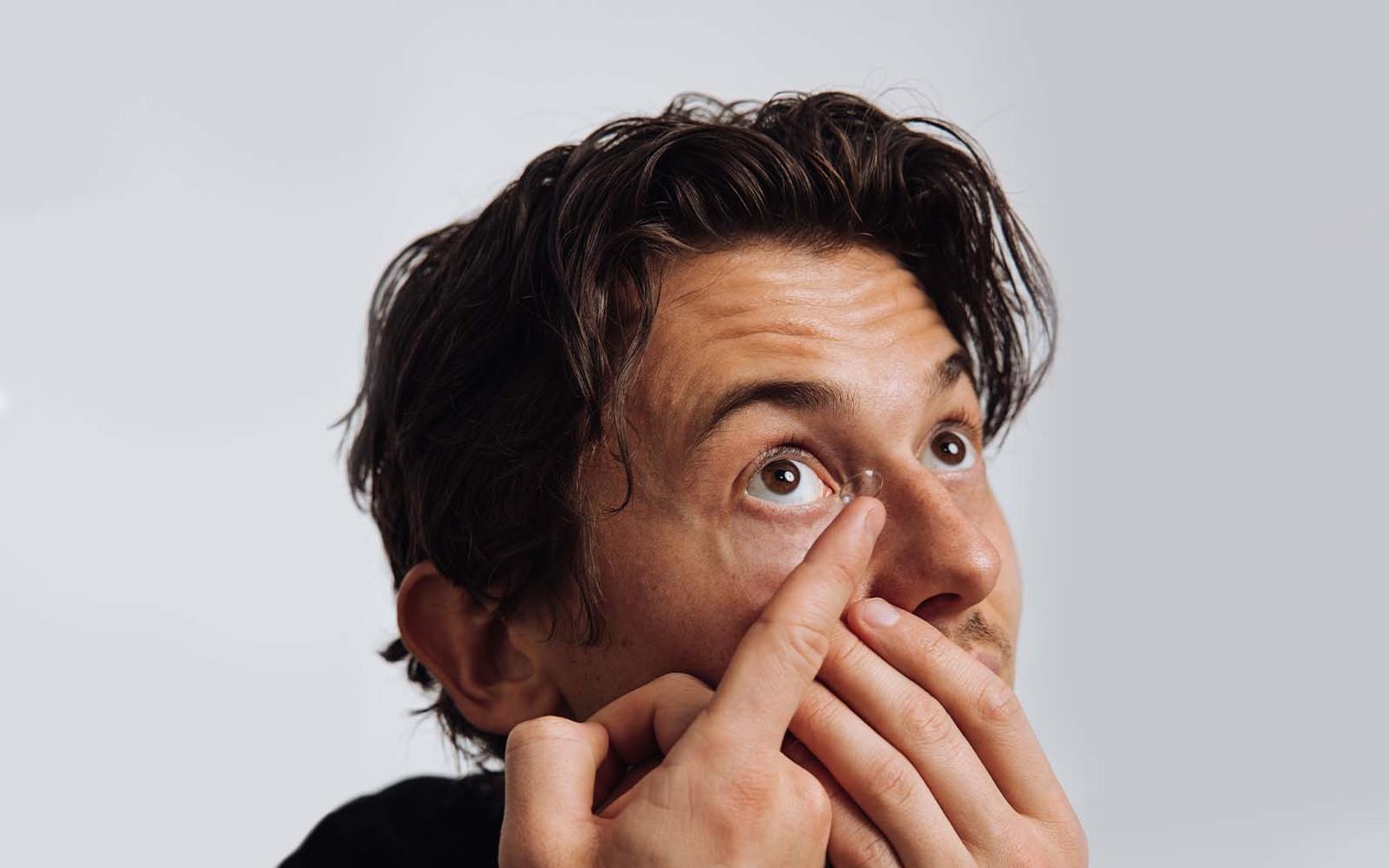 En mann ser opp i taket og tar på kontaktlinser