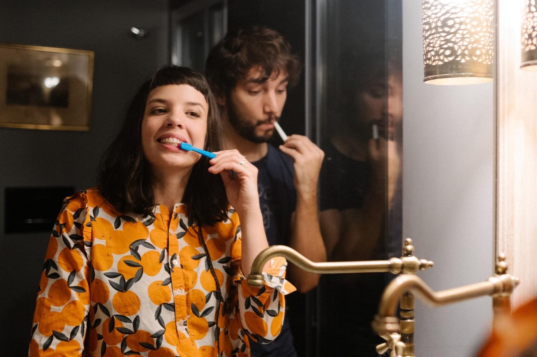 Speilbilde av et ungt par som står på baderommet og pusser tennene sammen.