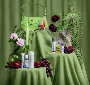 Bilde av en liten grønn veske på en pidestall med grønn duk. I forkant presenteres produkter som kan være nyttige på storbyferie.