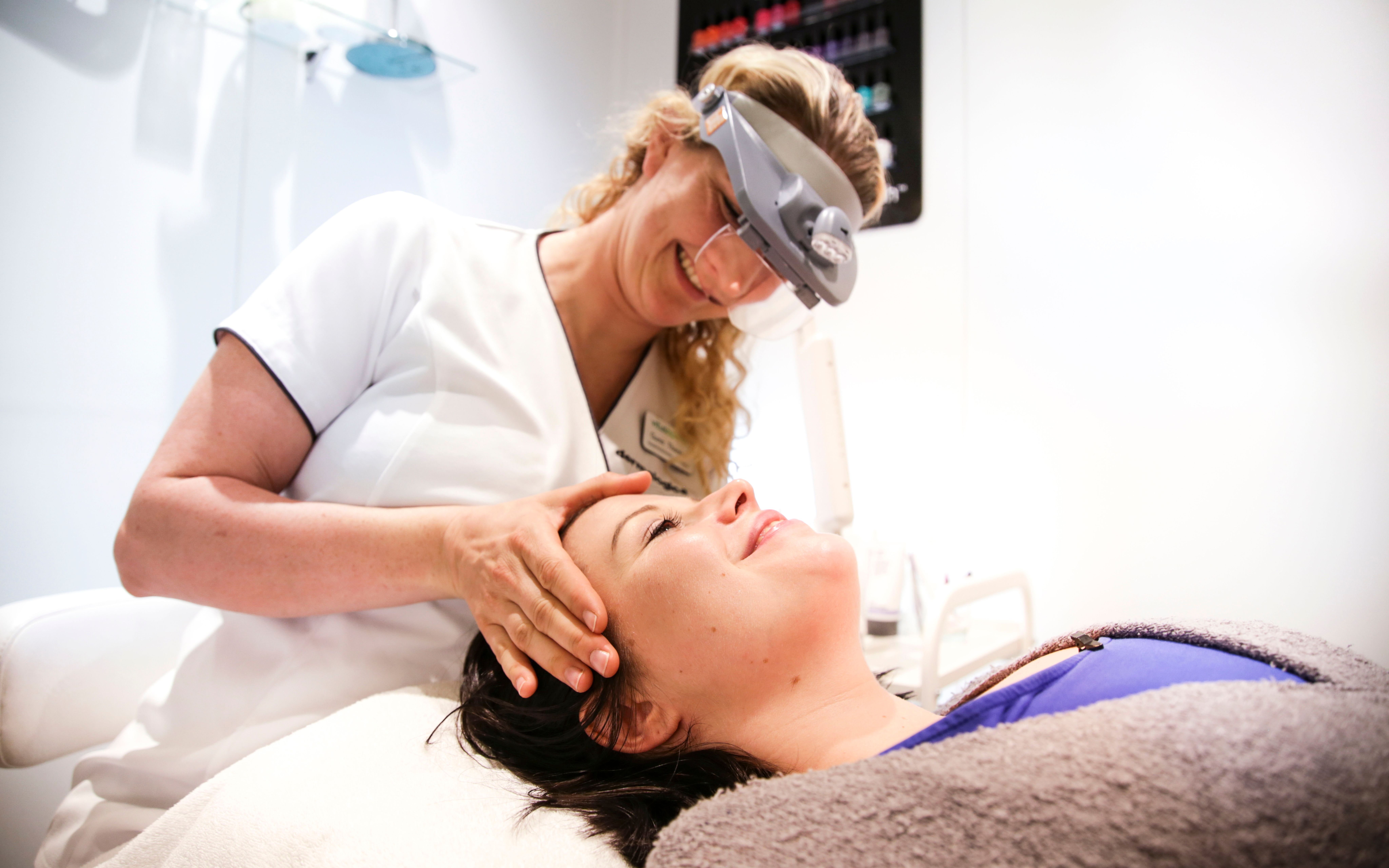 En kvinne ligger og blir undersøkt av en hudpleier