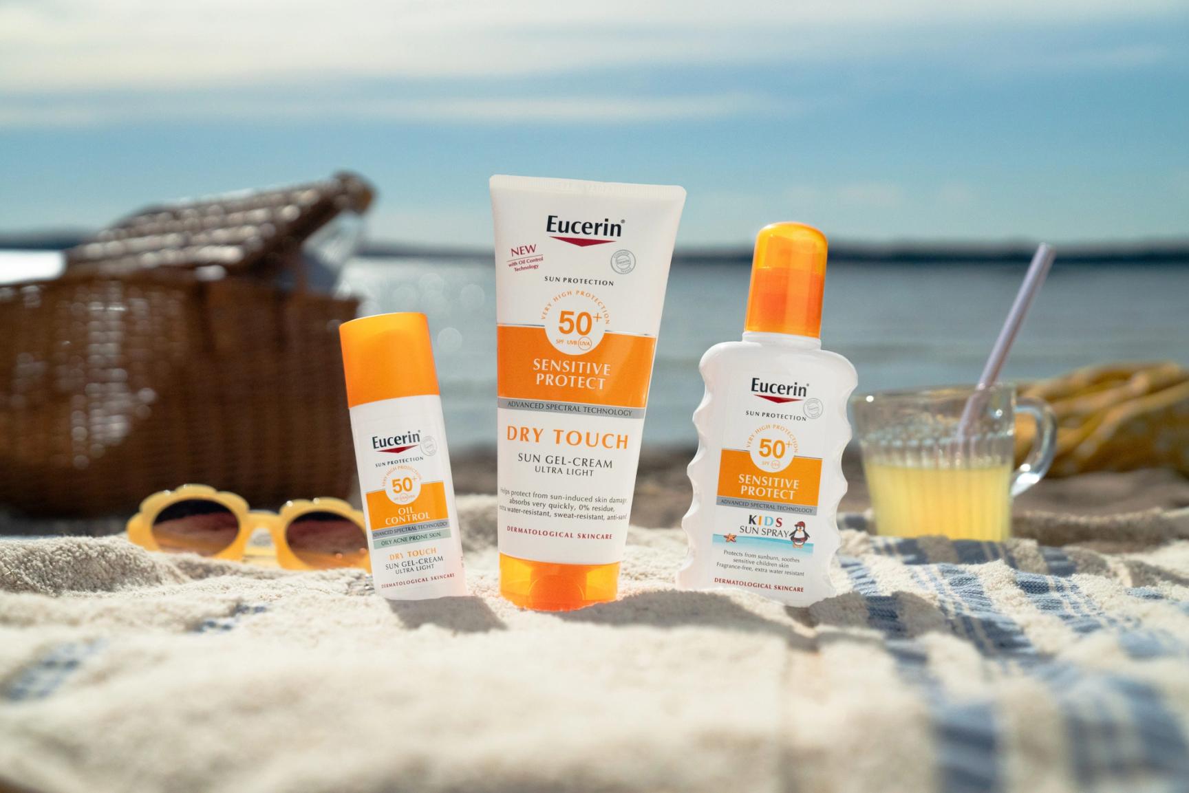 Bilde av solbriller og Eucerin solkrem på en strand