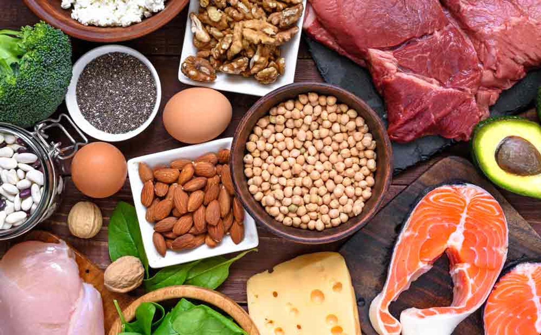 Bilde av fat med nøtter og bønner. Ved siden av ligger egg, nøtter, grønnsaker og fisk