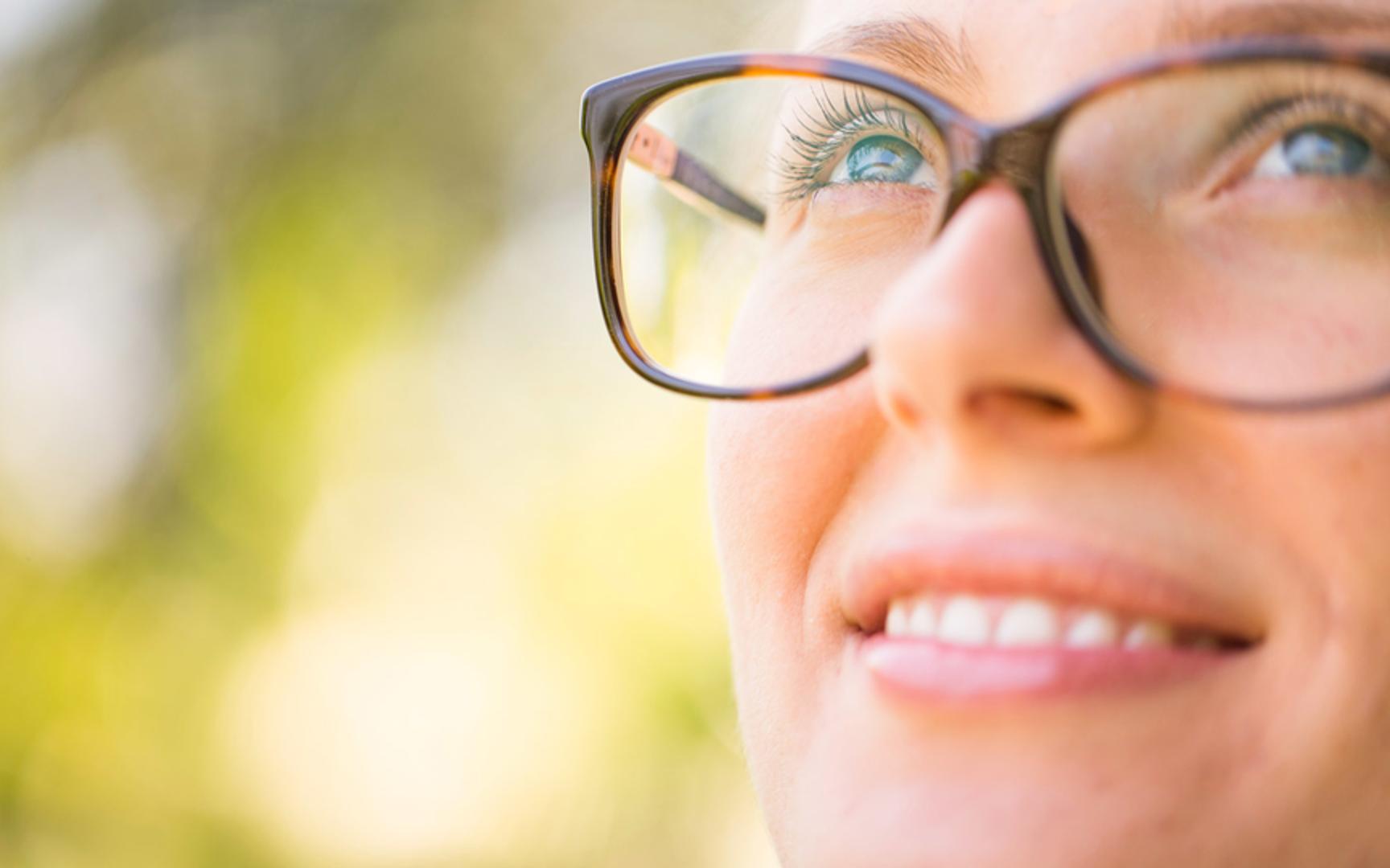 Kvinne som smiler opp mot solen