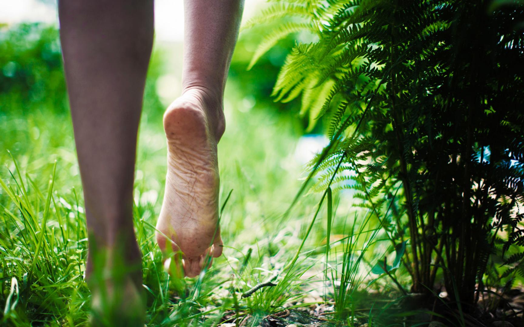 Bilde av to føtter som går i gresset, hvor man ser under den ene foten.