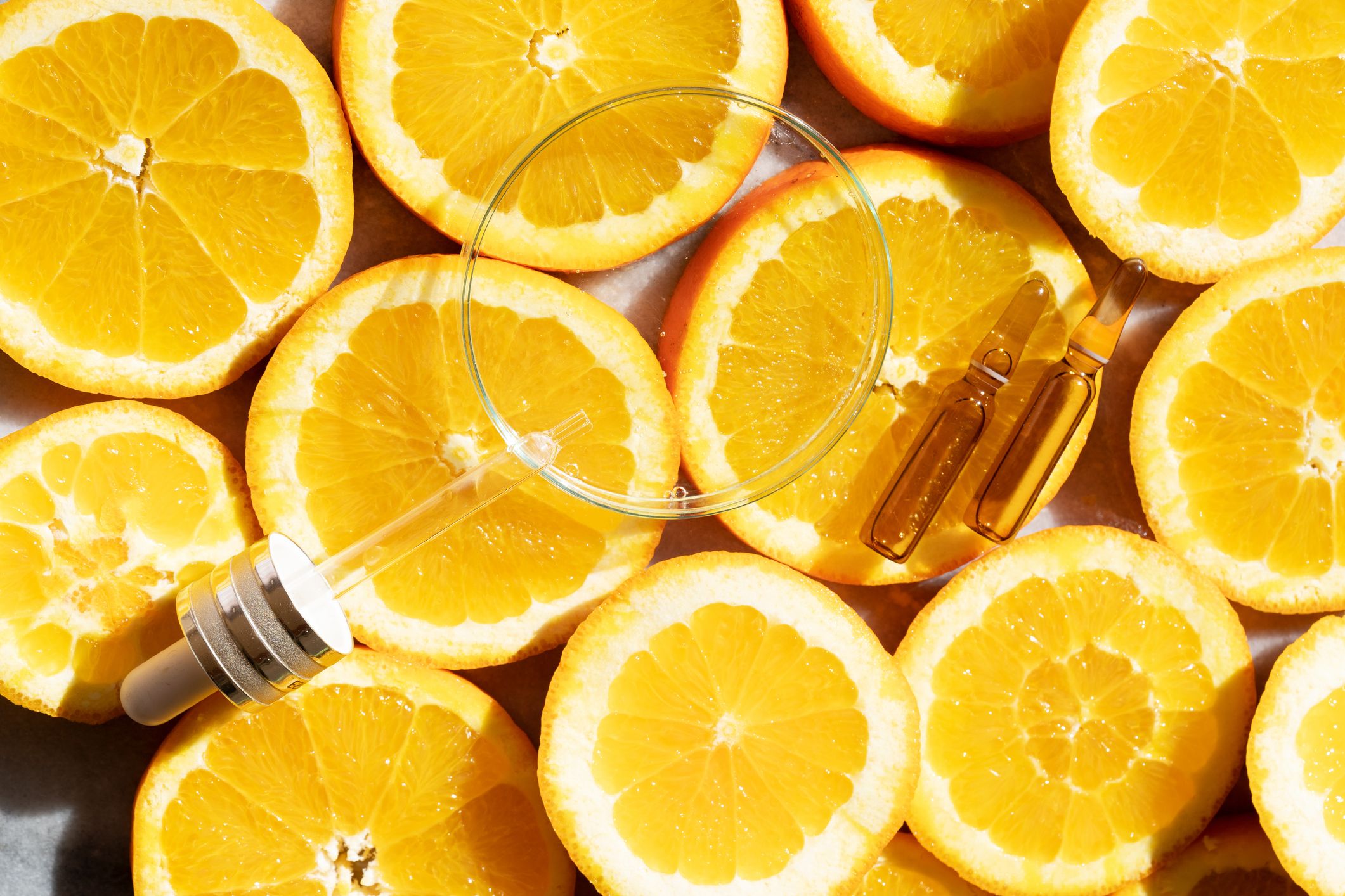 Skivede appelsiner med pipette og ampuller for hudpleieserum.