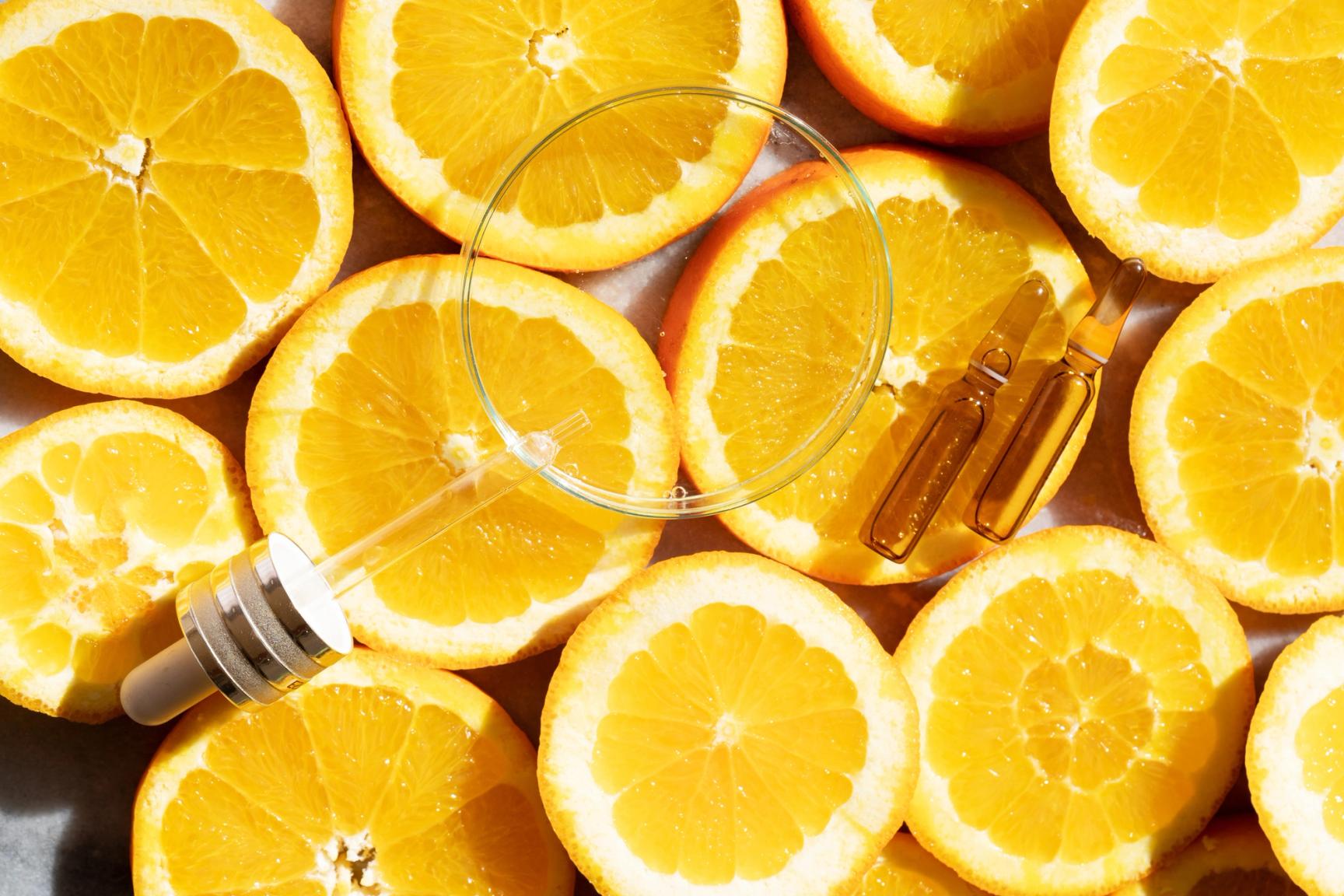 Skivede appelsiner med pipette og ampuller for hudpleieserum.