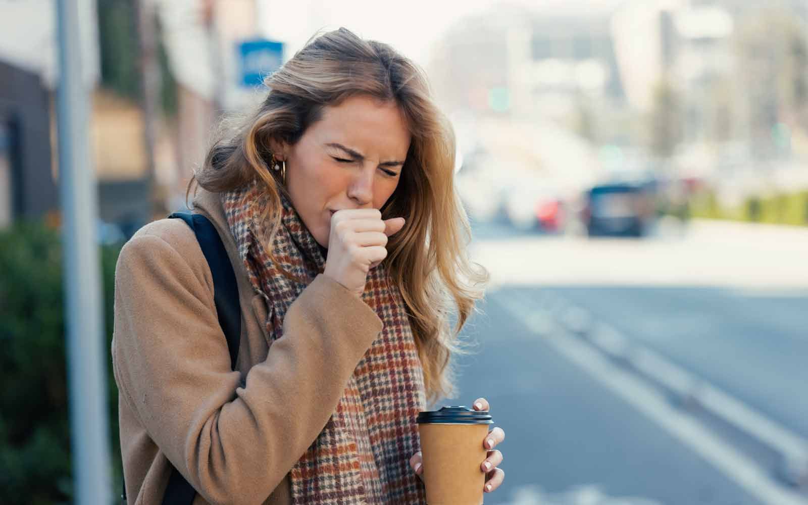 Ung kvinne holder seg for munnen og hoster