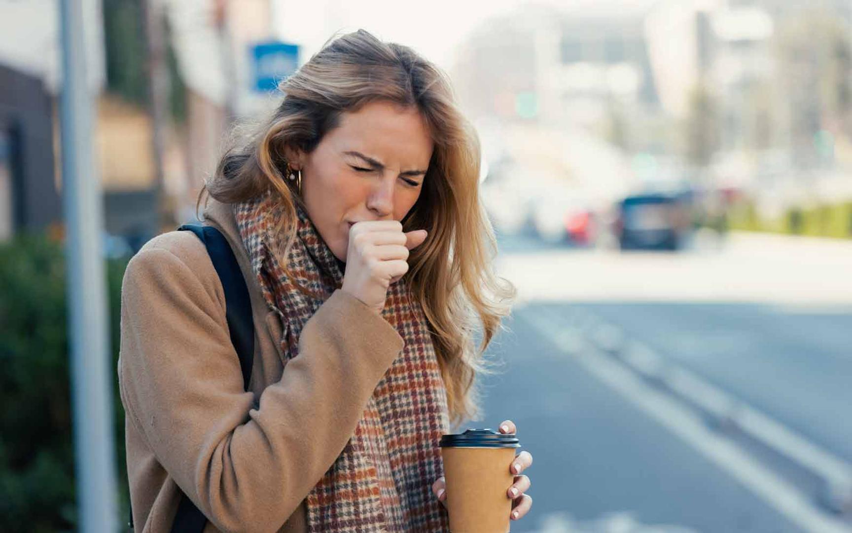 Ung kvinne holder seg for munnen og hoster