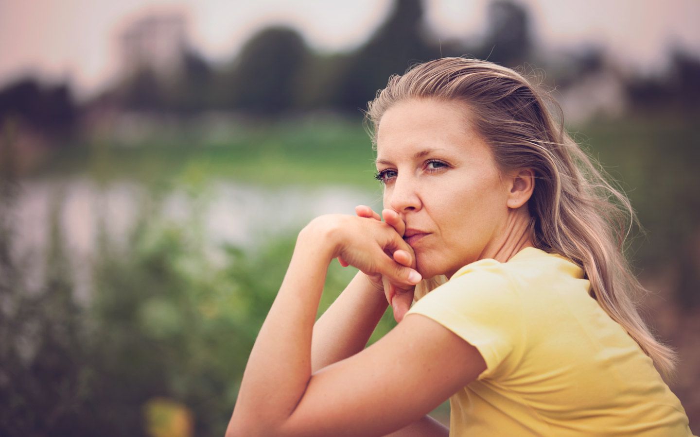 Bilde av dame med smalt blikk som ser holder hendene under haken og ser tankefull ut