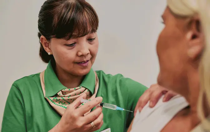 Apotektekniker setter en vaksine i armen til en kunde.